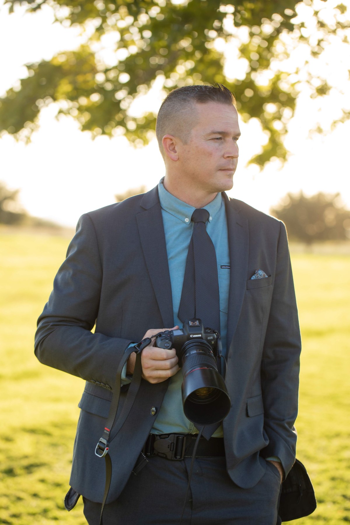 Trevor Dayley in a suit with camera in hand at a wedding